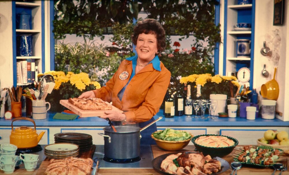 Julia Child in her kitchen, cooking and smiling