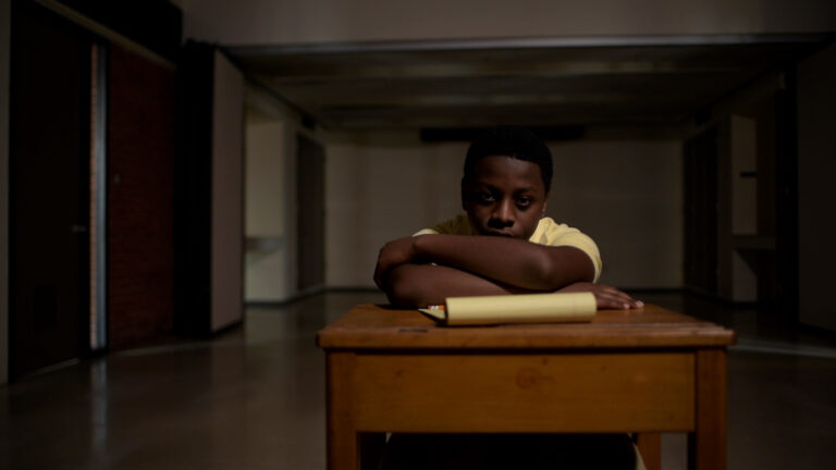 Pensive boy at desk with paper, likely related to the "Juvenile: Five Stories" blog.