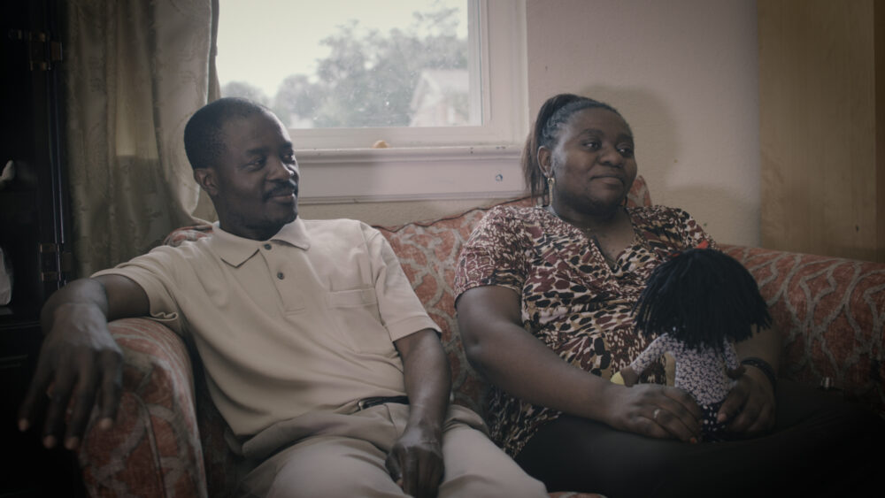 Couple sitting on a couch with a doll, "Know Your Neighbor" blog content.