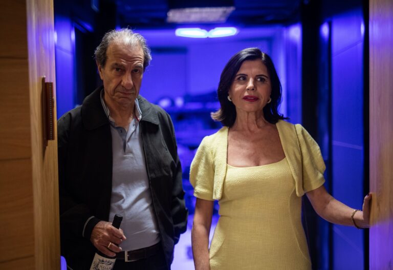 Well-dressed couple entering a karaoke room, man holding wine.