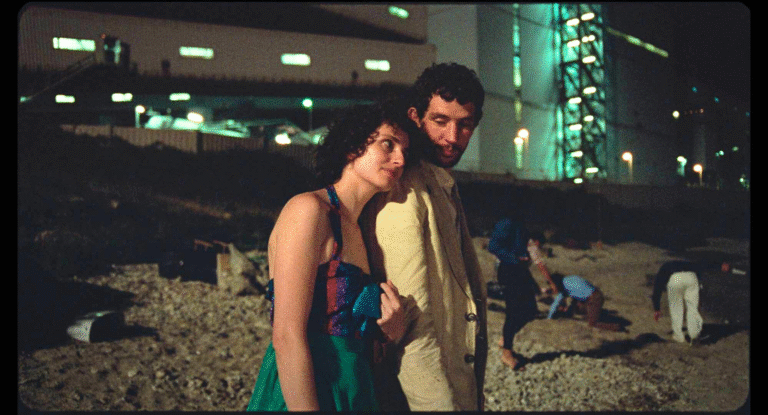 Couple embracing at night with industrial backdrop, possibly related to "La Chimera.