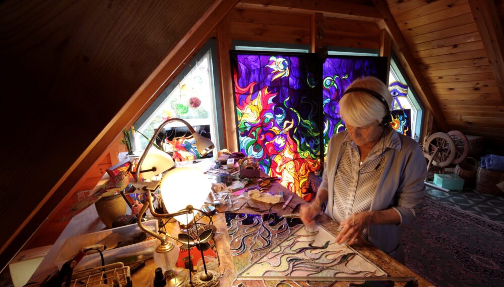 Artist crafting stained glass art in a charming attic studio.