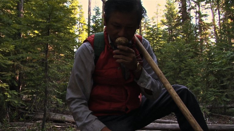 Man in forest smelling a truffle, possibly from "The Last Season"