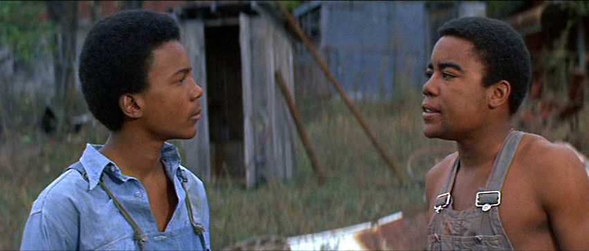 Two young Black boys in "The Learning Tree" look at each other outdoors.