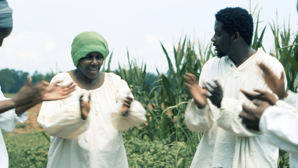 African Americans clapping and dancing in a field.