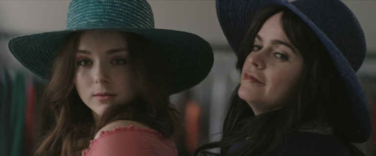 Two women posing with wide-brimmed hats.