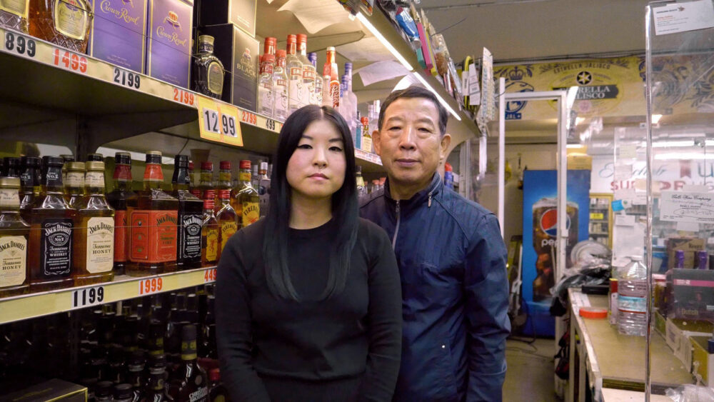 Owners of a local liquor store stand in front of shelves stocked with Crown Royal and Jack Daniel's.