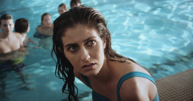 Woman in a pool looking concerned, with other people swimming in the background.