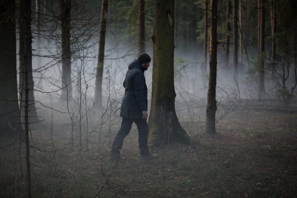 Man walking alone through a misty forest. Dark and loveless atmosphere.