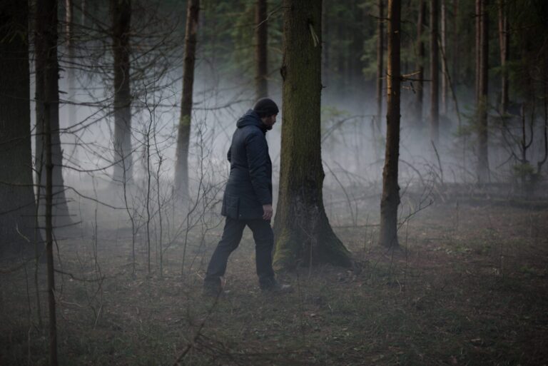 Man walking alone through a misty forest. Dark and loveless atmosphere.