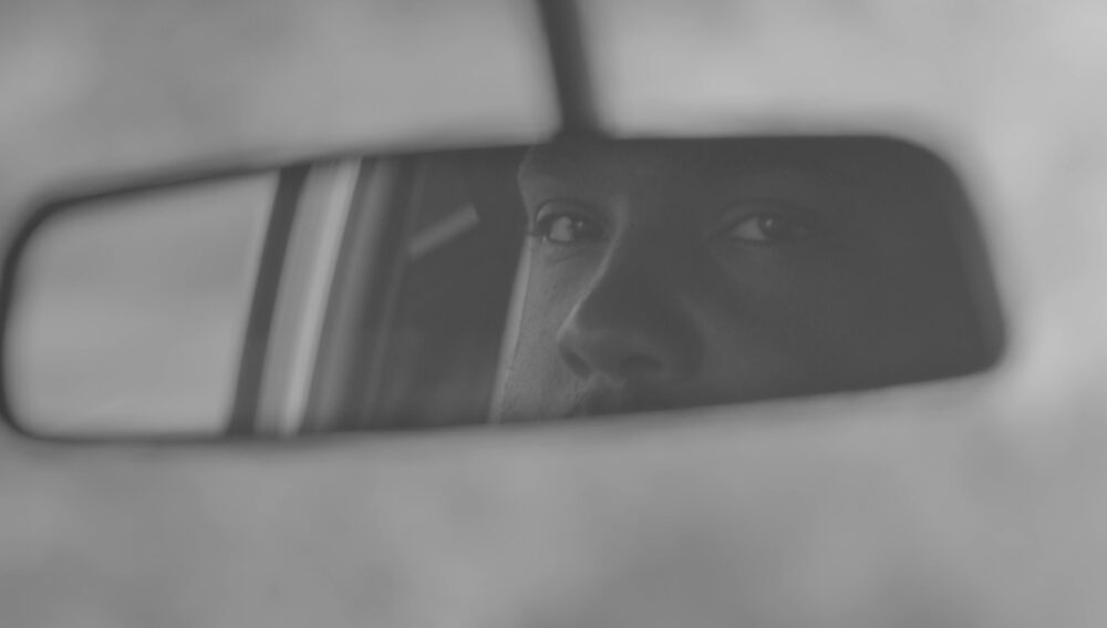 Man's reflection in a car's rearview mirror.