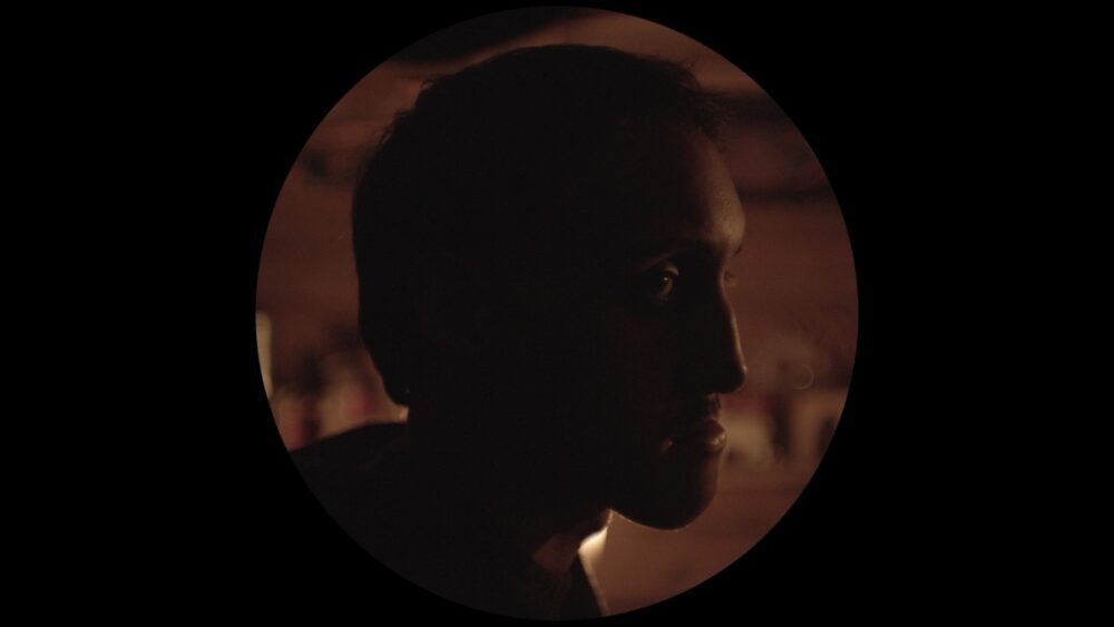 Silhouette of a man's face in dim lighting, evoking a sense of mystery.