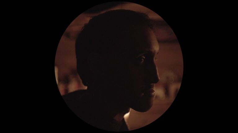 Silhouette of a man's face in dim lighting, evoking a sense of mystery.