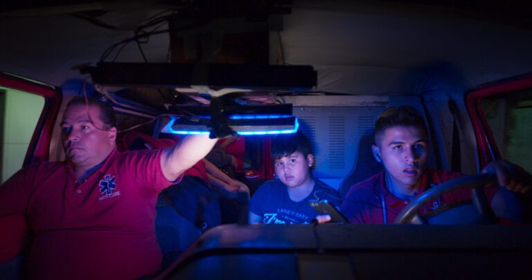 Midnight Family: Three people inside an ambulance at night.