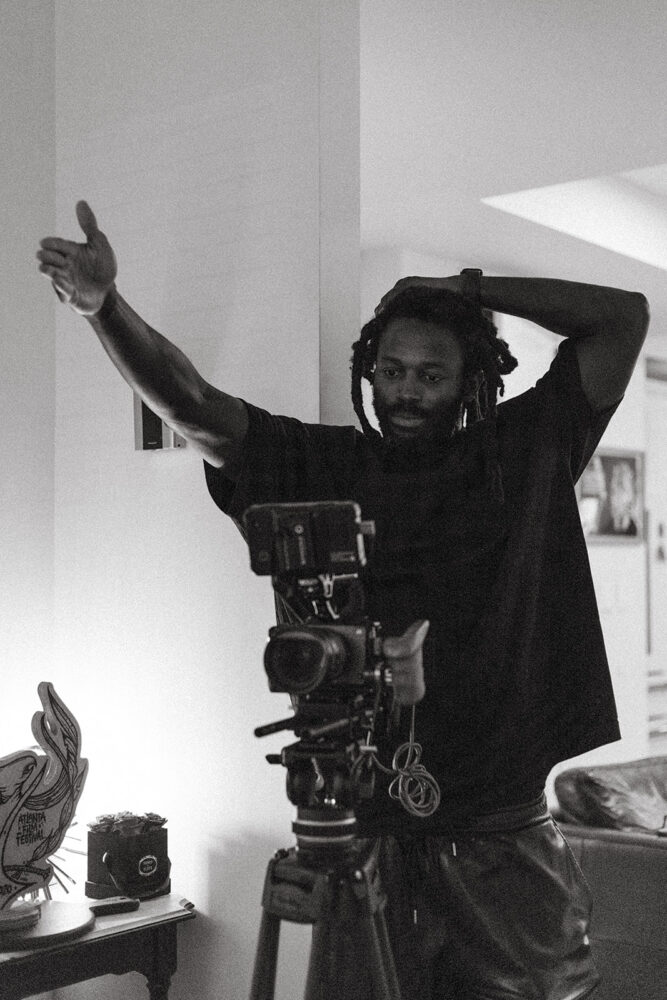 Filmmaker Maba Ba gesturing behind a professional camera setup in a home studio.