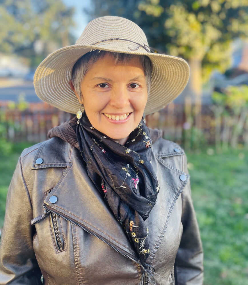 Mabel Valdiviezo wearing a hat and scarf, smiling outdoors.