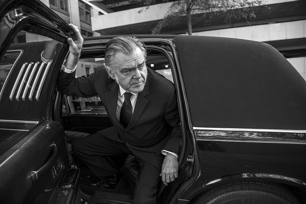 Man in suit exiting a limousine.