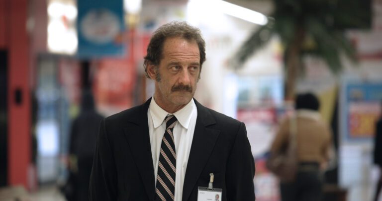 Man in suit with name tag in shopping center.
