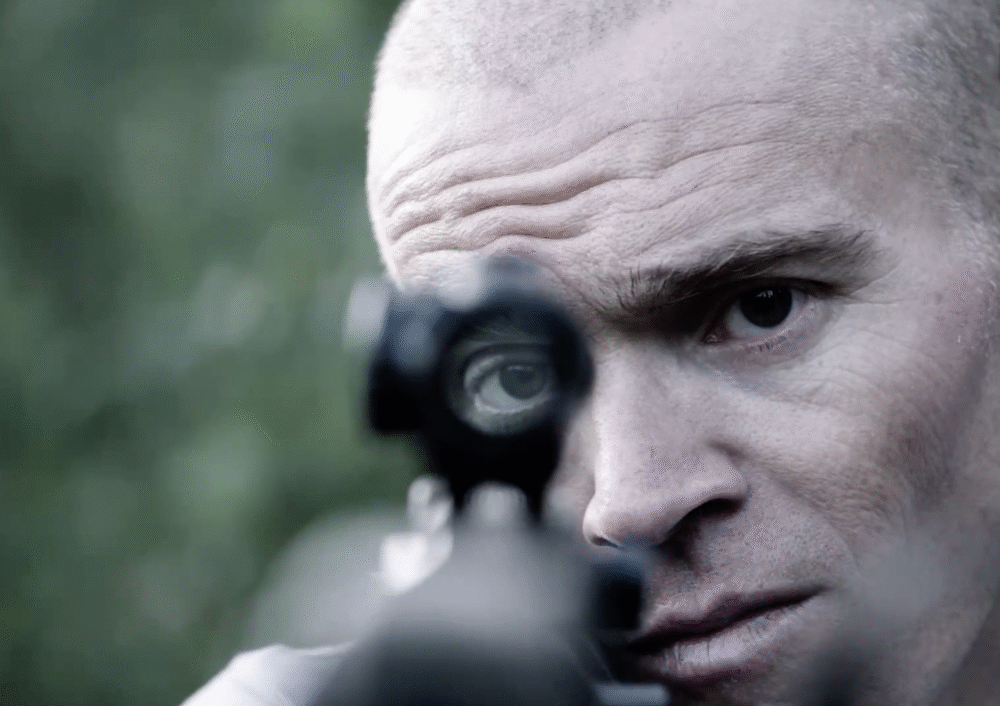 Man aiming a rifle with focused expression, evoking themes of "Men of War.