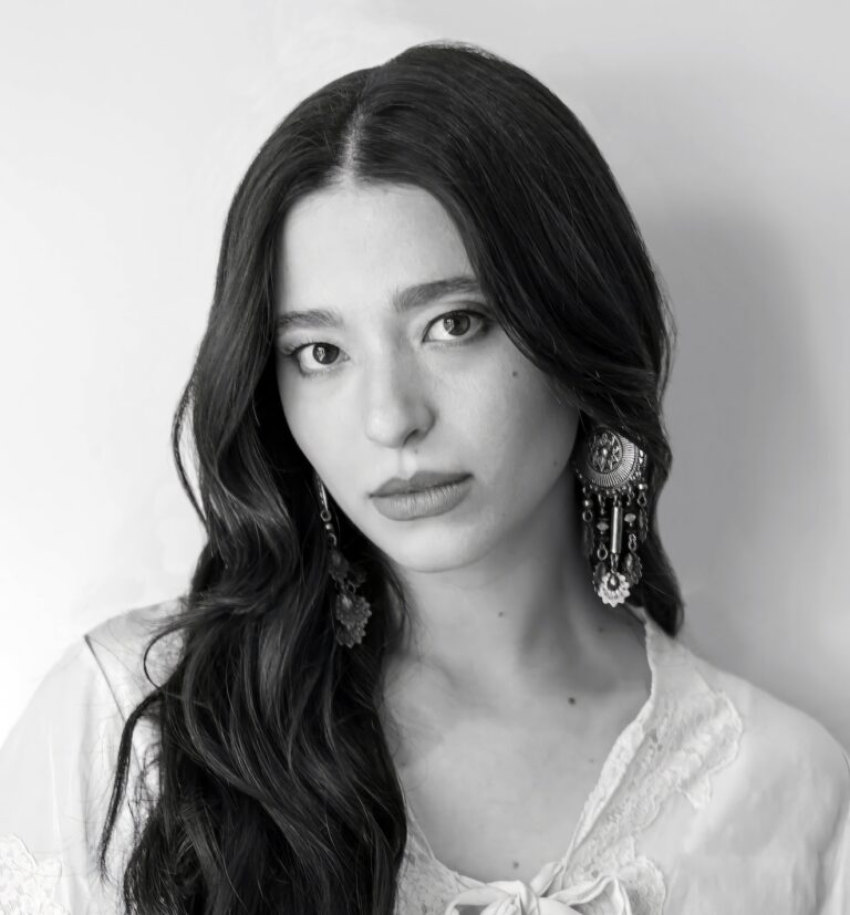 Black and white portrait of actress Mikey Madison wearing statement earrings.