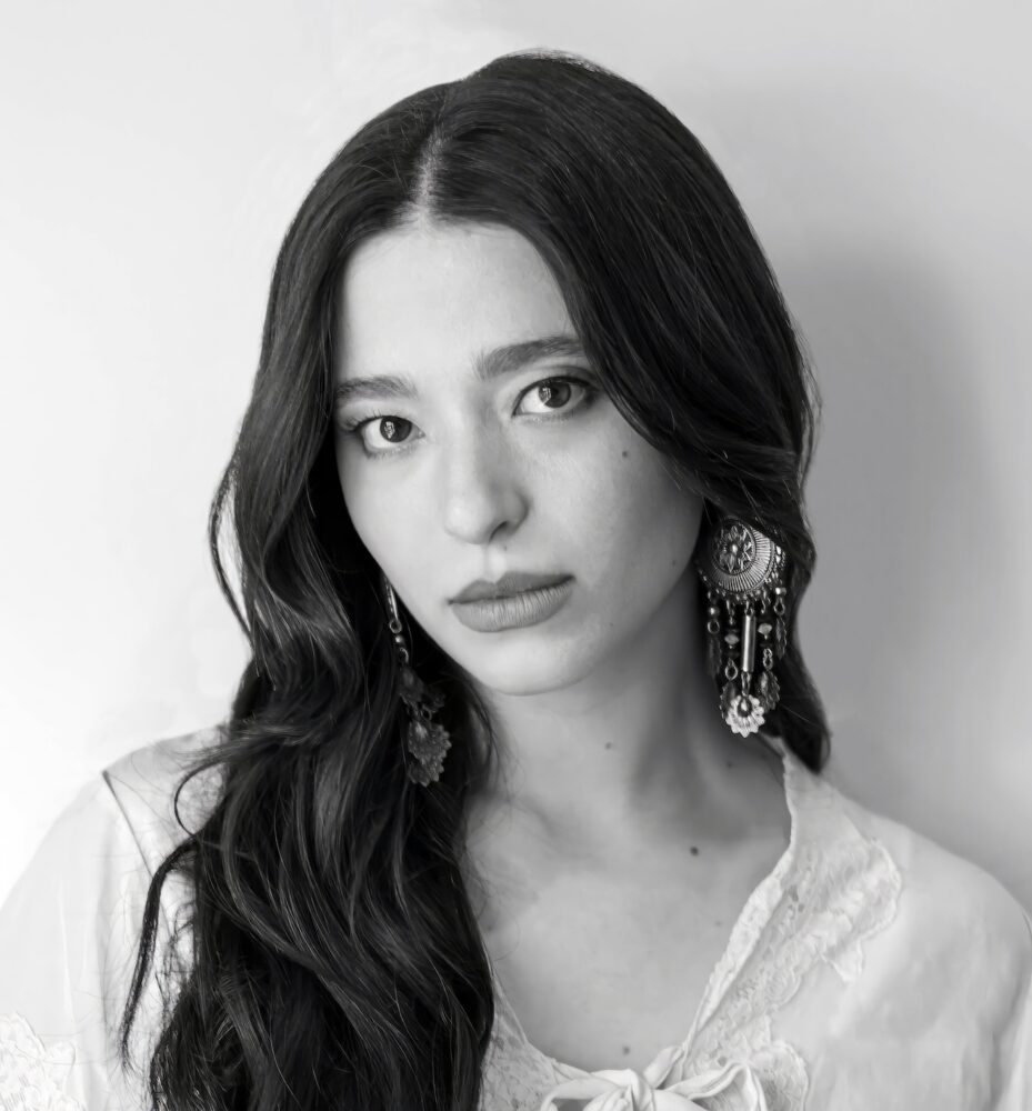 Black and white portrait of actress Mikey Madison wearing statement earrings.