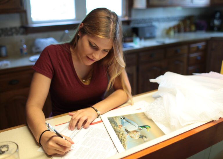 Woman signs paperwork next to a duck print.