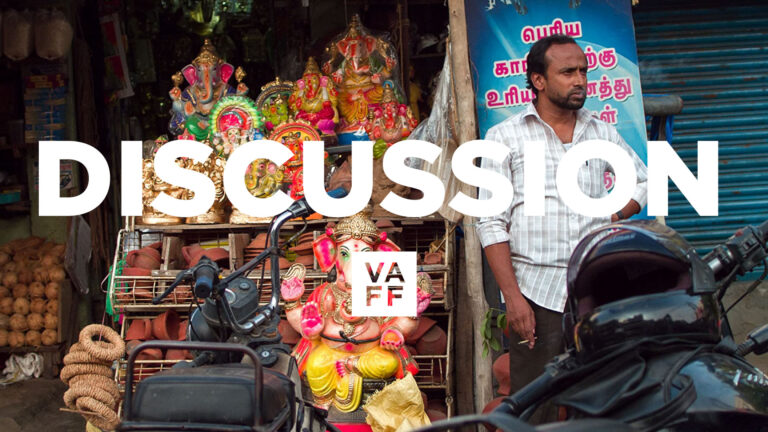 Nasir discussion: Man stands near Ganesha statues and motorbikes.