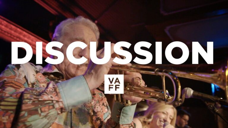 Doc Severinsen playing trumpet at a "Never Too Late" discussion. Vaff logo.