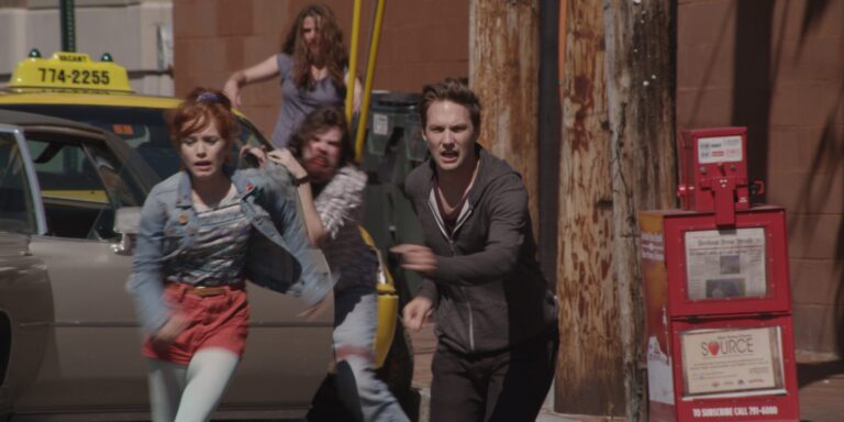 Frightened people running from zombies near a taxi in "Night of the Living Deb"