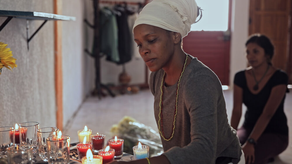 Woman with headwrap lighting candles at an altar.
