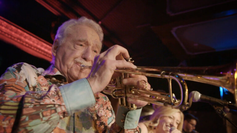 Doc Severinsen playing the trumpet, close-up at a performance.