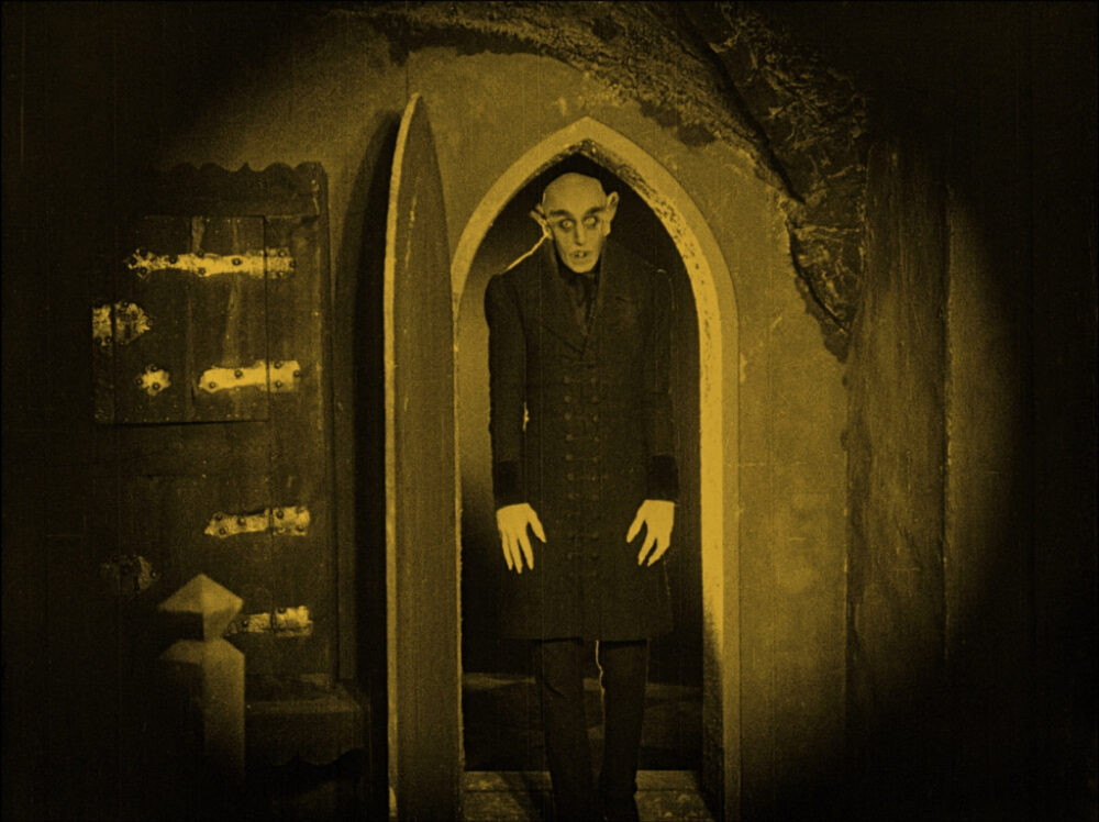 Nosferatu emerges from a doorway, classic vampire horror film.