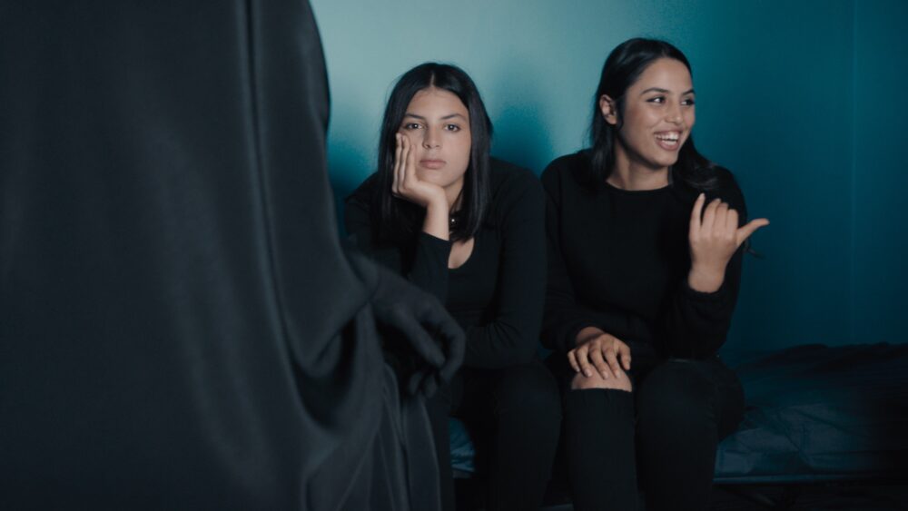 Two women react to a cloaked figure.