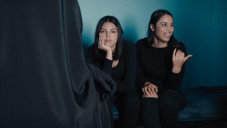 Two women react to a cloaked figure.