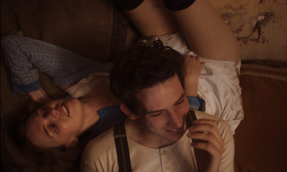 Couple smiling, lounging on a couch in "Mothering Sunday