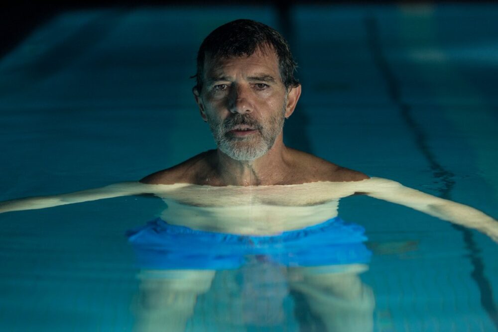Antonio Banderas in "Pain and Glory," standing in a pool wearing blue shorts.