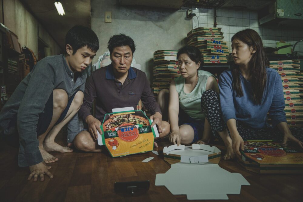 The Kim family folding pizza boxes in the movie Parasite.