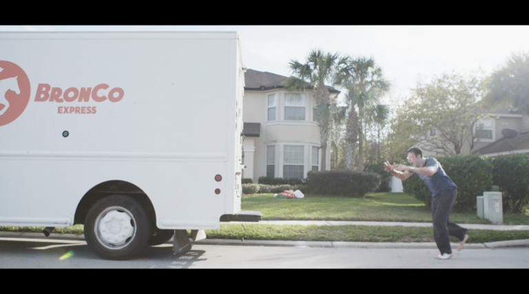 Man chasing a Bronco Express delivery truck on a residential street.