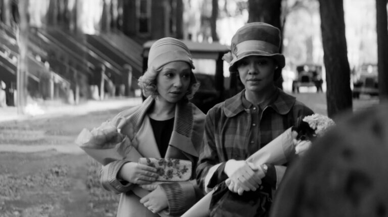 Black and white still from the movie "Passing," featuring two women with flowers.