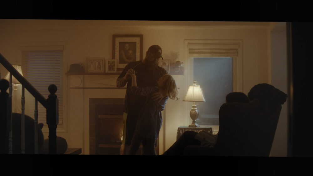 Dad dancing with child by fireplace in cozy living room.
