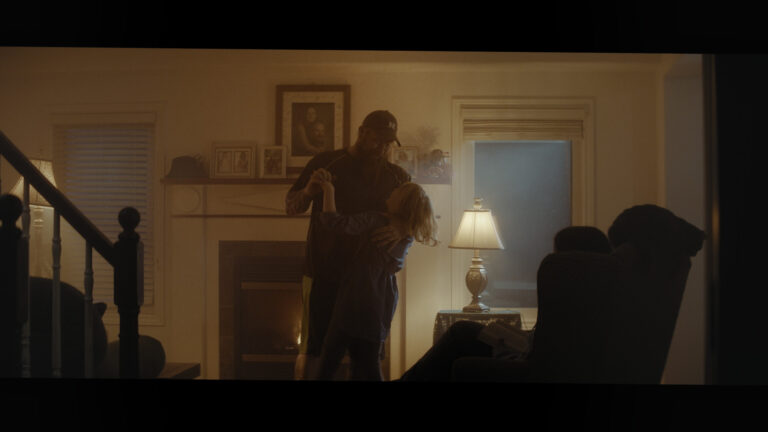 Dad dancing with child by fireplace in cozy living room.