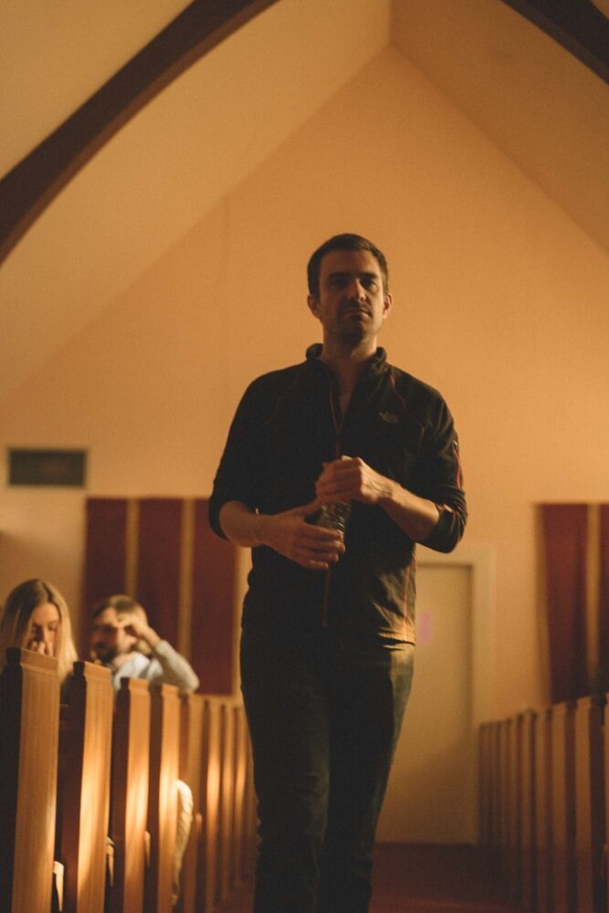 Man walking down church aisle, holding water bottle