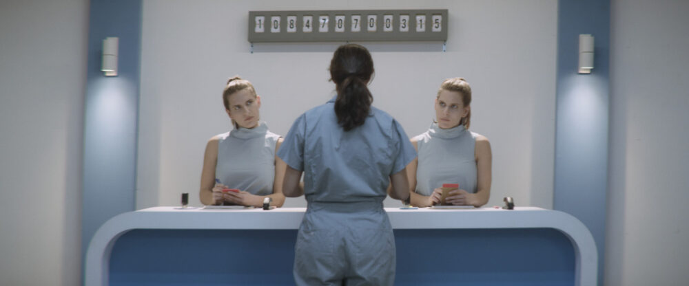 Two women behind a desk with a counter above displaying numbers.