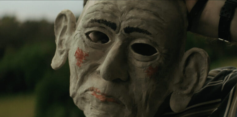 Creepy mask with large ears, red cheeks, and dark eye holes.