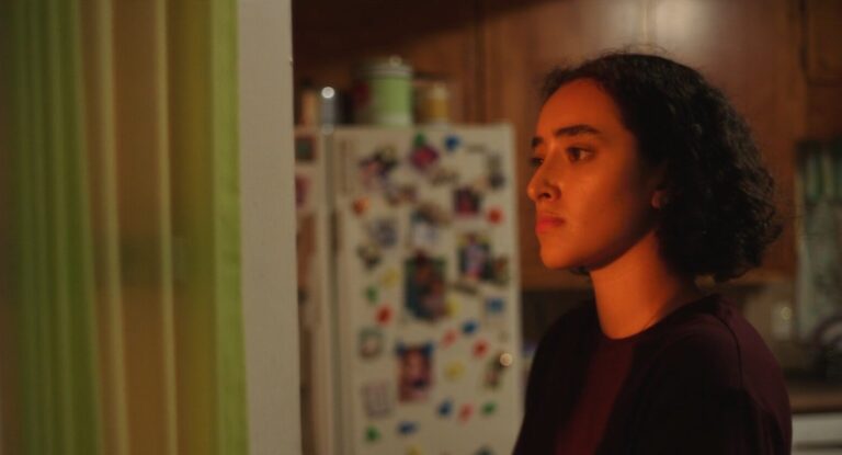 Pensive woman in kitchen with warm lighting, looking off to the side