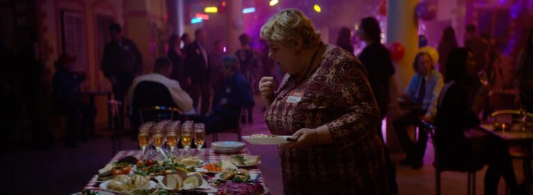 Woman at buffet with "Anna" name tag in a crowded party.