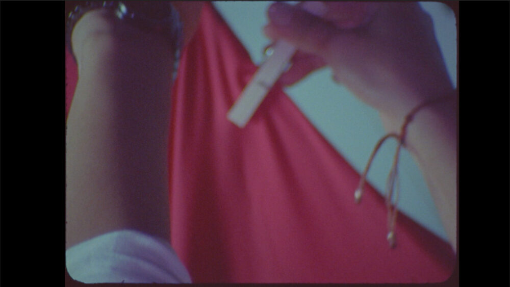 Close-up of a hand holding a pregnancy test against a red background.