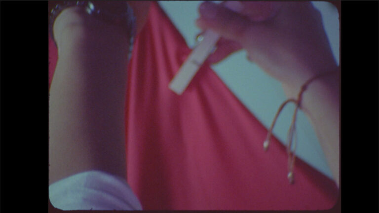 Close-up of a hand holding a pregnancy test against a red background.