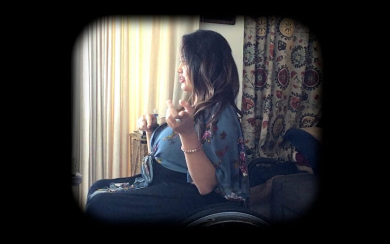 Woman in wheelchair looks out window, lost in thought.
