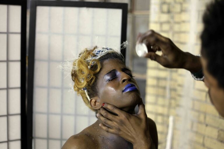 Person with blue lipstick and glitter being styled for Pier Kids.